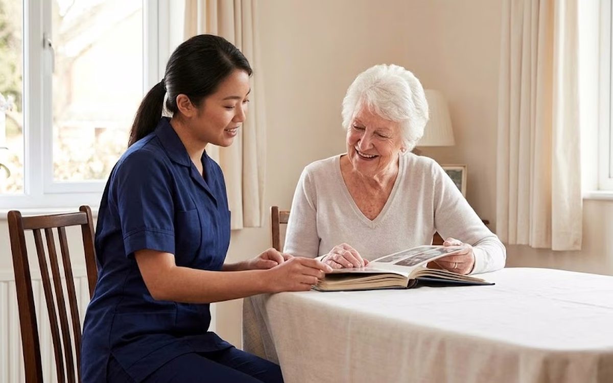 A Dendera Care carer looking through a photo album together with an older woman at the table
