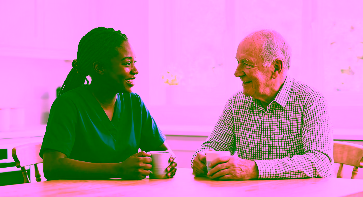 A Dendera Care carer and an older man sharing tea and conversation
